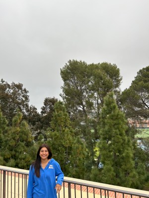 Photo of Violeta smiling on campus on a cloudy day wearing a blue UCLA sweatshirt. 