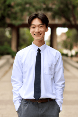 Photo of Jaden on UCLA's campus smiling at the camera and wearing a white shirt and black tie. 