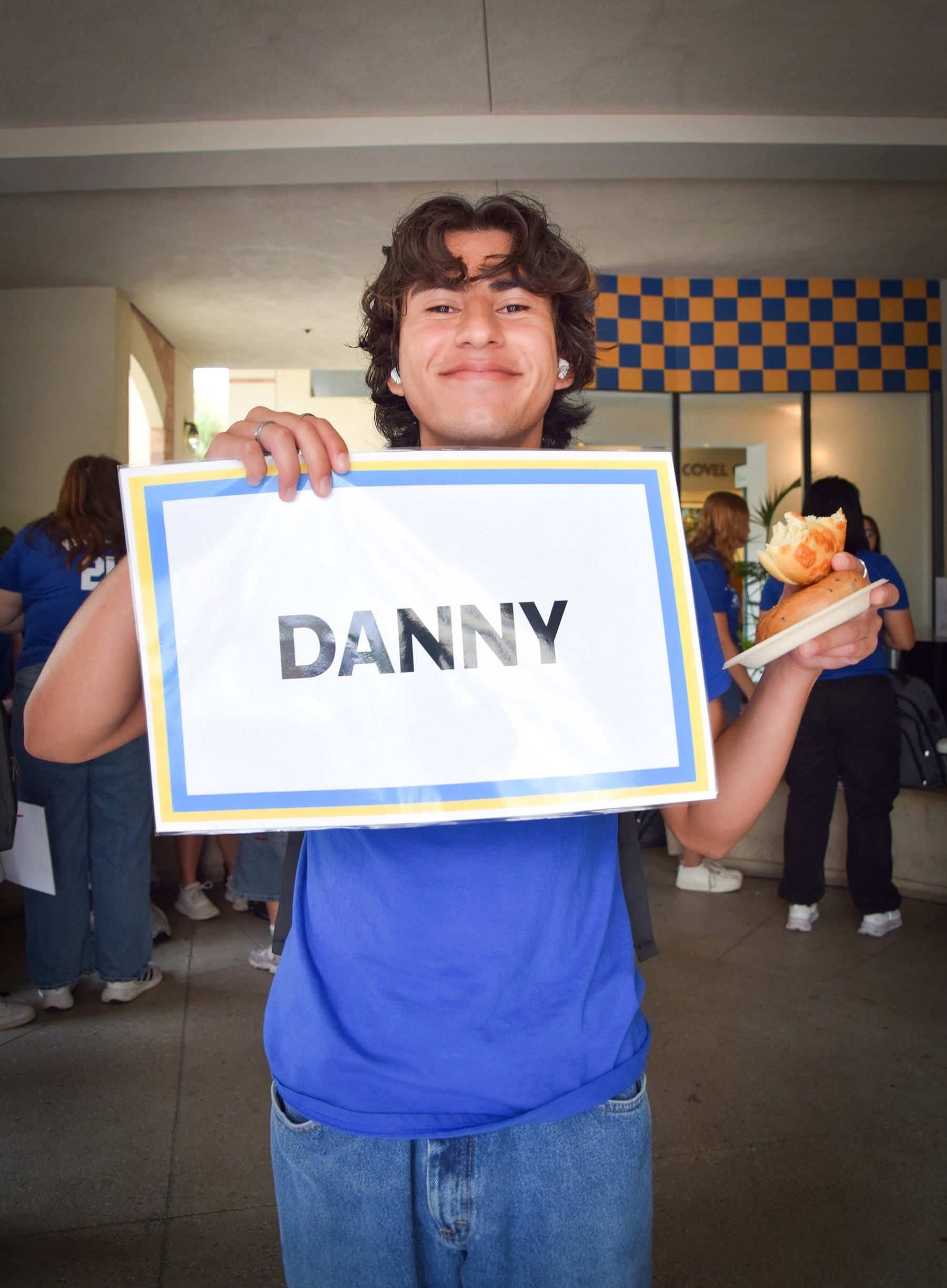 Photo of Danny during a resident event wearing a blue shirt, smiling and holding a sign with his name on it.