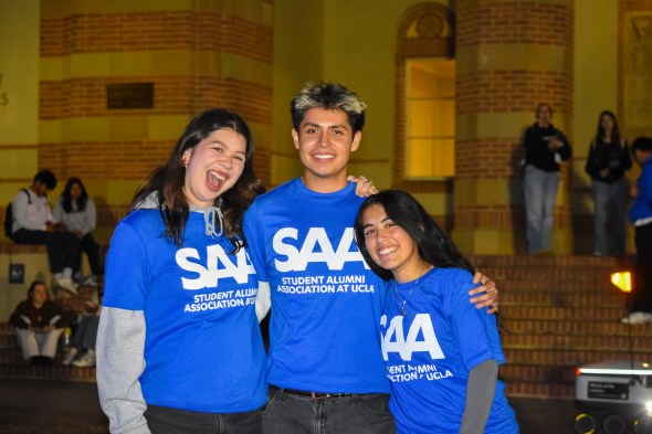Kathryn smiling with two other student members of the Student Alumni Association (SAA) at UCLA during the Beat 'SC Rally all wearing blue SAA t-shirts.