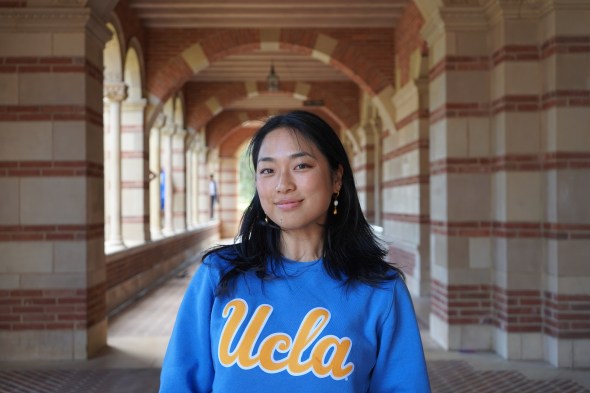 Amy standing outside of Royce Hall at UCLA wearing a blue UCLA crewneck. 