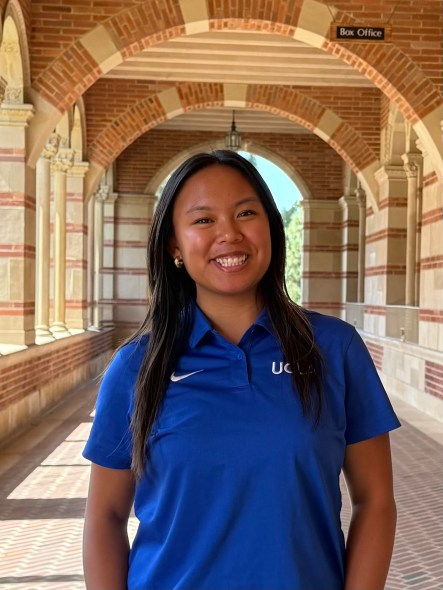 Camille outside of Royce Hall wearing a blue UCLA polo shirt. 
