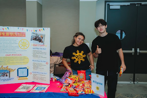 Isabella and a friend reprsenting the Pilipinx LLC at the annual LLC Welcome Reception standing next to a poster board with information about their LLC.