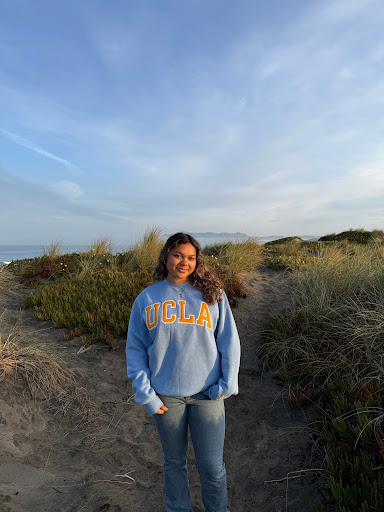 Isabella at the beach wearing a blue and gold UCLA sweatshirt.