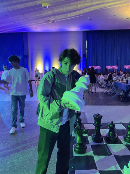 Samuel posing holding a large chess piece at a UCLA event. 