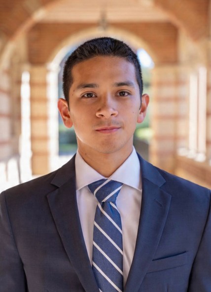 Professional photo of Matthew wearing a suit and standing in the hallway outside of Royce Hall at UCLA.